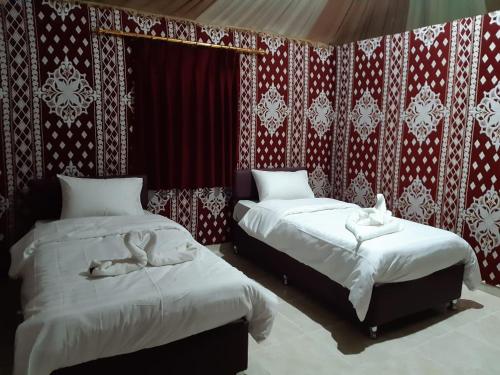 two beds in a room with red and white wallpaper at Sand Star Camp in Wadi Rum