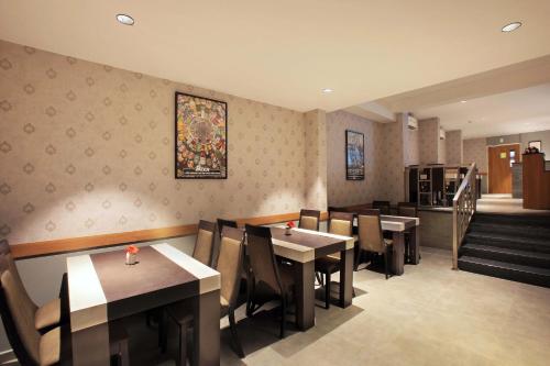 a restaurant with tables and chairs and a staircase at Hotel Samrat in Taliparamba