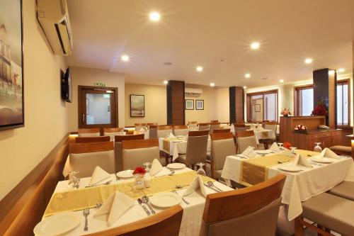 a restaurant with tables and chairs in a room at Hotel Samrat in Taliparamba