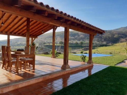 - un pavillon en bois avec une table et des chaises sur la terrasse dans l'établissement Casa rural Quinta de los Almiares, à Candeleda