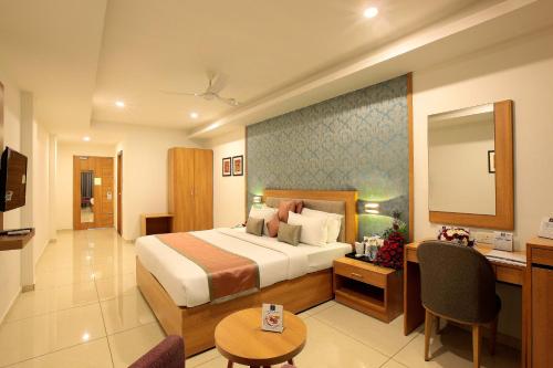 a hotel room with a bed and a desk at Hotel Samrat in Taliparamba
