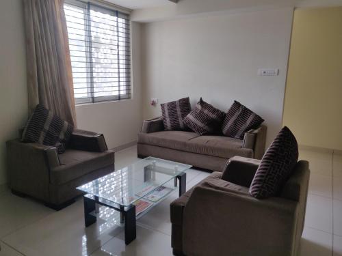 a living room with two couches and a glass table at Suvarna Compact in Mysore