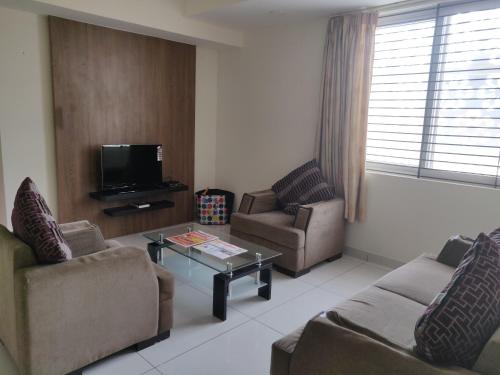 a living room with two couches and a tv at Suvarna Compact in Mysore