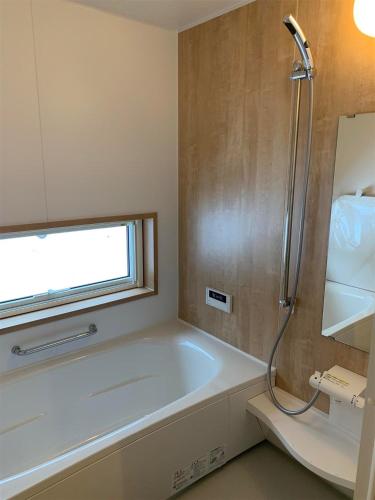a bathroom with a bath tub and a window at Kalamunda House Rusutsu in Rusutsu