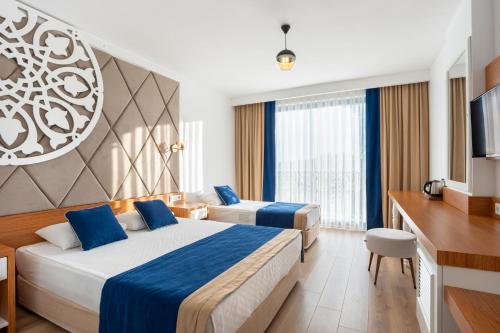 una camera d'albergo con due letti e una televisione di The Sansa Hotel & Spa a Manavgat