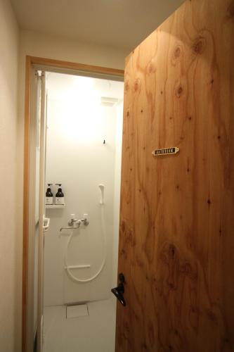 a bathroom with a toilet and a wooden door at guesthouse SHIBAFU in Kamakura