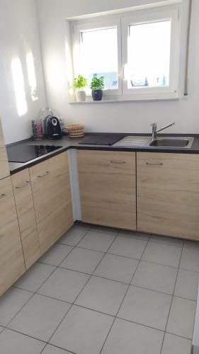 a kitchen with wooden cabinets and a sink and two windows at 4* Ferienwohnung Neukirchen im Erzgebirge in Adorf