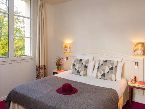 een slaapkamer met een bed met een hoed erop bij Mercure Rambouillet Relays Du Château in Rambouillet
