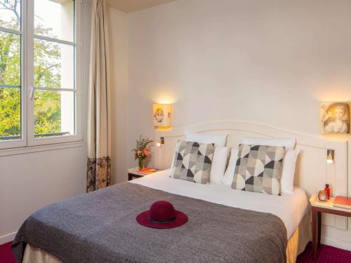 a bedroom with a bed with a hat on it at Mercure Rambouillet Relays Du Château in Rambouillet