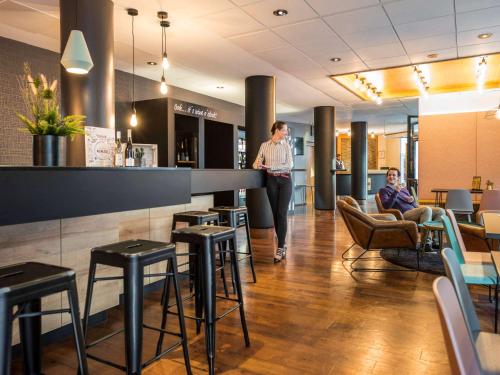 a woman standing at a bar in a restaurant at Mercure Hotel Berlin Zentrum Superior in Berlin