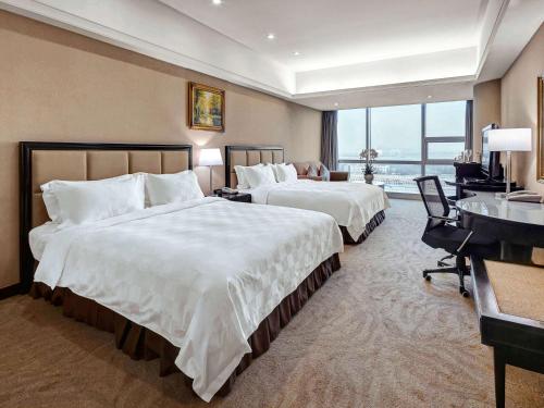a hotel room with two beds and a desk at Oriental Ginza Hotel Shenzhen in Shenzhen