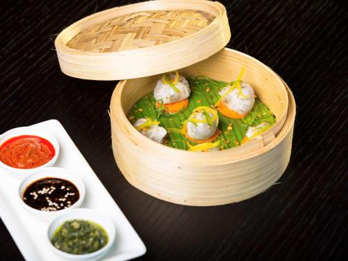 a wooden bowl of food with dumplings and sauce at Novotel Chennai Sipcot in Chennai