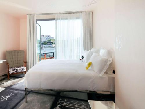 a bedroom with a white bed and a large window at Mama Shelter Lyon in Lyon