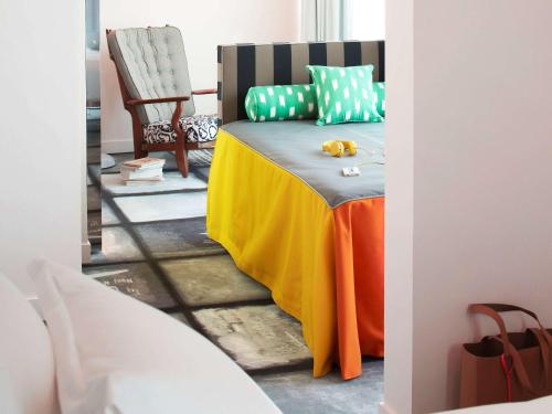 a bedroom with a bed with a yellow blanket and a chair at Mama Shelter Lyon in Lyon