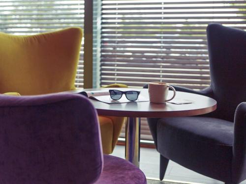 a table with a pair of glasses on it with chairs at Mercure Sheffield Parkway in Sheffield