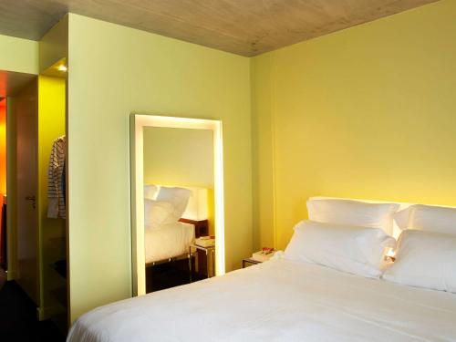 a bedroom with a white bed and a mirror at Mama Shelter Lyon in Lyon