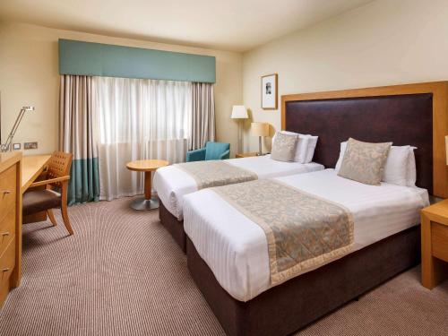 a hotel room with two beds and a desk at Mercure Sheffield Parkway in Sheffield