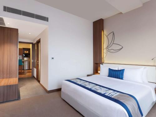 een slaapkamer met een groot wit bed en een blauw kussen bij Mercure Chennai Sriperumbudur in Sriperumbudur