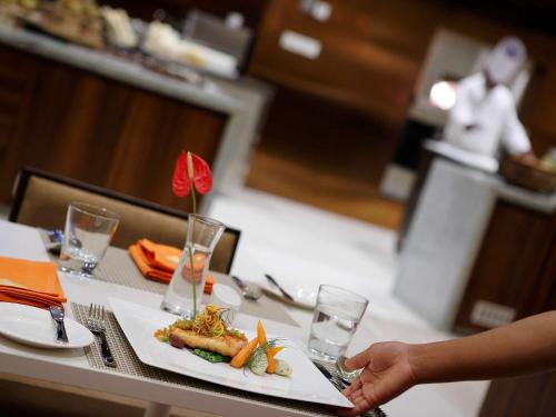 a person holding a plate of food on a table at Novotel Chennai OMR in Chennai