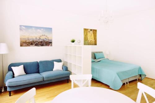 a living room with a blue couch and a bed at Herzlich Willkommen - Küss die Hand in Vienna