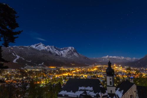 a city at night with mountains in the background at Gästehaus Hohe Tannen in Garmisch-Partenkirchen
