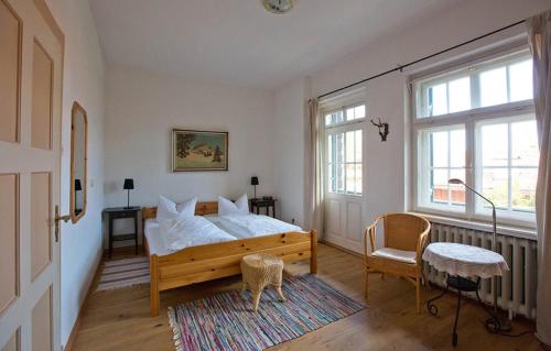 a bedroom with a bed and a chair and a window at Gästehaus Hohe Tannen in Garmisch-Partenkirchen