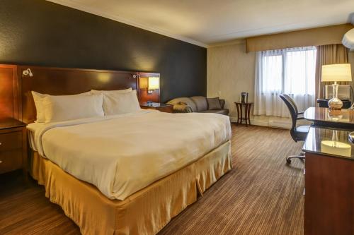 Habitación de hotel con cama grande y escritorio. en La Saguenéenne - Hôtel et Centre de Congrès en Saguenay