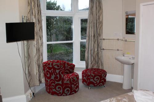 a bathroom with two chairs and a sink and a window at The Darnley Hotel in Ilfracombe