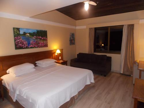 a bedroom with a large white bed and a couch at Apart-hotel em Gramado, padrão 4 estrelas, no centro in Gramado