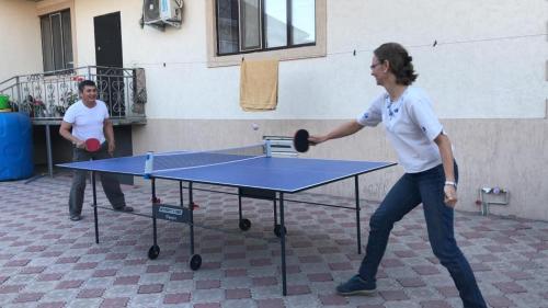 a woman swinging a racket at a ping pong table at Guest House EtnoDom in Jalal-Abad