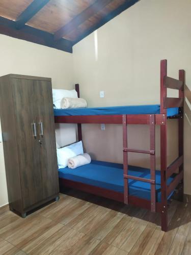 two bunk beds in a room with a cabinet at Acomodação chalé entre capitolio e escarpas do lago in Capitólio