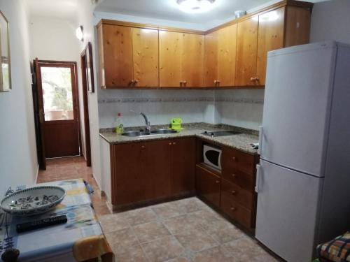 Apartamentos Aguas Verdes في لاس بالماس دي غران كاناريا: مطبخ بدولاب خشبي وثلاجة بيضاء