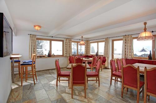 a restaurant with red chairs and tables and windows at Residenz Scherrhof in Kirchberg in Tirol
