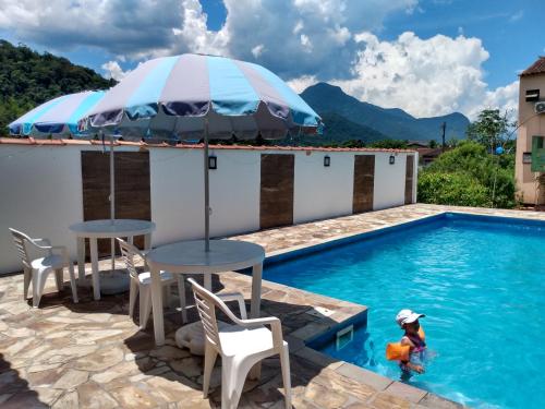 ein Pool mit einem Tisch und einem Sonnenschirm im Wasser in der Unterkunft Repouso Clave de Sol in Paraty