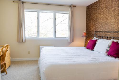 a bedroom with a large white bed with pink pillows at Vantage Point Villas at Stratton Mountain Resort in Stratton Mountain