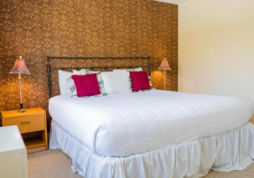 a bedroom with a large white bed with red pillows at Vantage Point Villas at Stratton Mountain Resort in Stratton Mountain