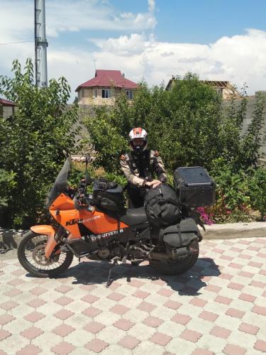 a man is sitting on an orange motorcycle at Guest House EtnoDom in Jalal-Abad