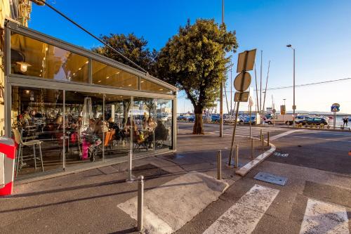 a store front with people sitting in chairs in a street at Molo Longo - Central Apartments & Rooms in Rijeka