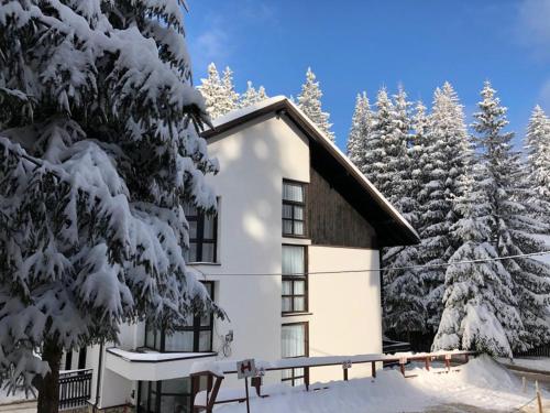 a house covered in snow in front of trees at Montana Residence in Poiana Brasov