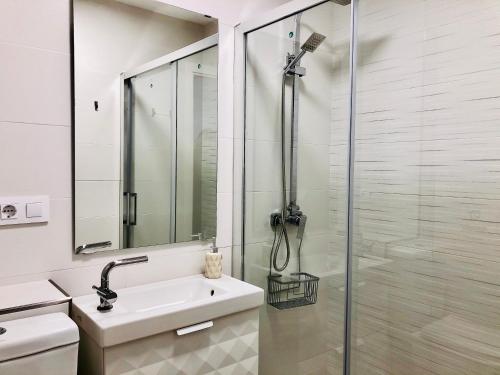 a white bathroom with a shower and a sink at Apartamento Ecuador in Cádiz