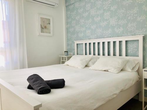 1 dormitorio con 1 cama blanca grande y papel pintado de color azul en Apartamento Ecuador, en Cádiz