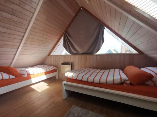 two beds in a attic room with a window at Ferienhaus mit eigenem Garten, 200m zum Strand, Gartensauna gegen Gebühr zubuchbar in Neukirchen
