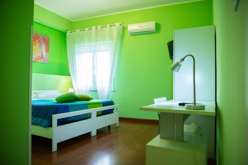 a green bedroom with a bed and a desk at Arcobaleno Guest House Pellaro in Pellaro