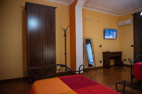 a bedroom with a bed and a dresser and a television at Arcobaleno Guest House Pellaro in Pellaro