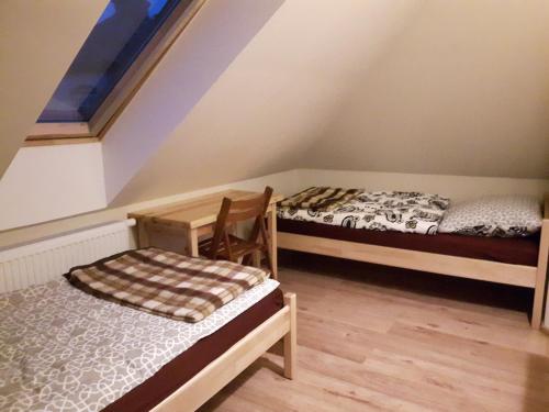 a attic room with two beds and a chair at Hotelik pod różą in Wójtowo