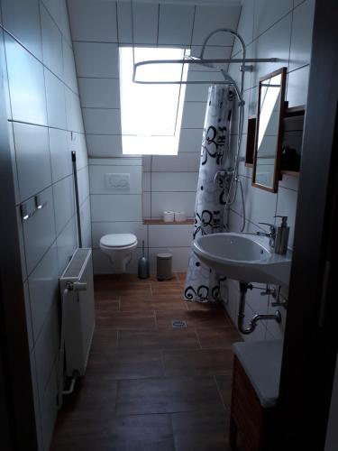 ein Bad mit einem Waschbecken, einem WC und einem Fenster in der Unterkunft Ferienwohnung Eiernest in Briedeler Heck