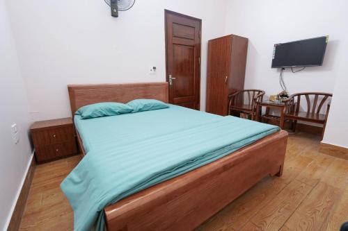 a bedroom with a bed with blue sheets and a flat screen tv at Motel Xuân Hòa in Bắc Ninh