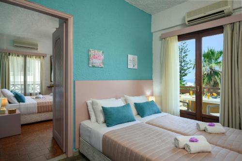 a bedroom with two beds with blue walls and a balcony at Alkion Hotel in Stalos