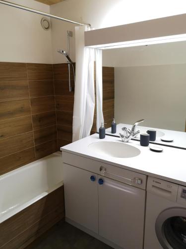 une salle de bain avec un lavabo, un miroir et une baignoire dans l'établissement Chalet Les Combes, à Notre-Dame-de-Bellecombe