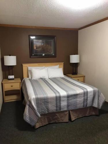 a hotel room with a bed with two nightstands and two lamps at Centerstone Resort Lake-Aire in Tomahawk